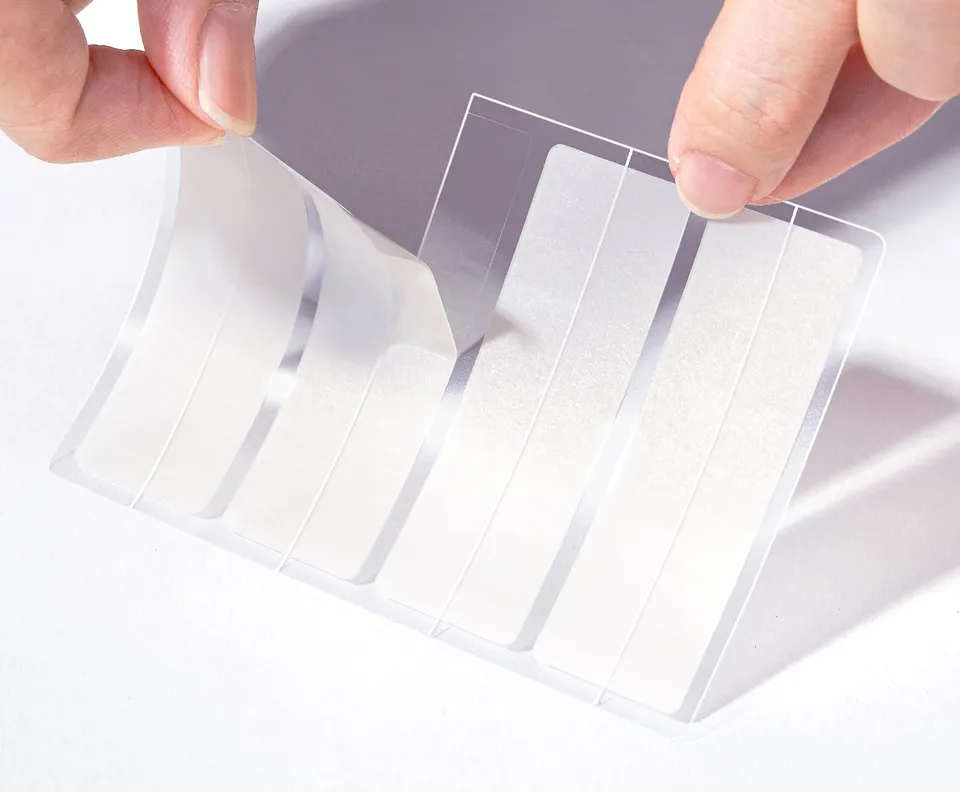 A hand peeling a TKTK hydrocolloid patch from its clear sheet